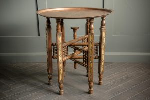 Indian style folding console table with engraved copper top sitting on 6 legs all with matching carved design.
